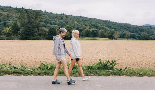 Two women walking in a scenic field, embracing wellness and an active lifestyle. Perfect representation of outdoor health and mindfulness.